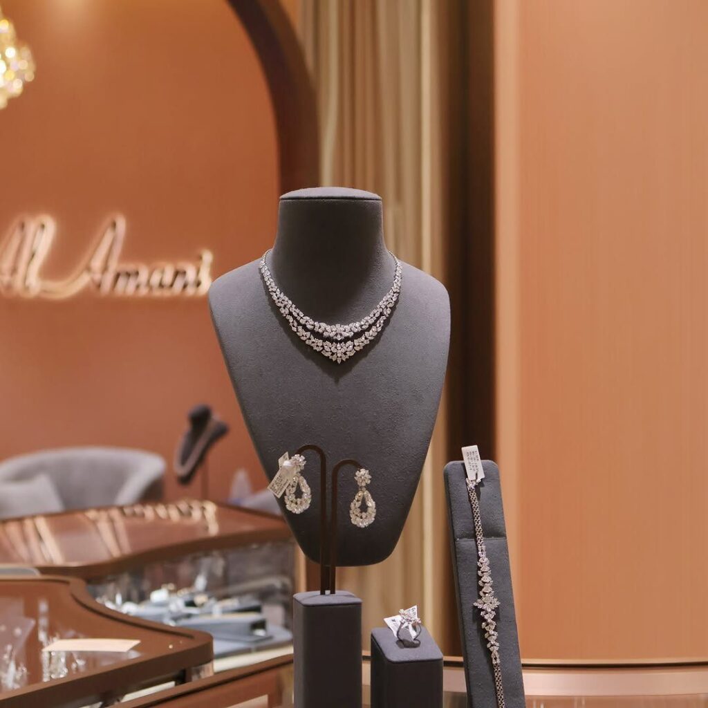 Diamond necklace, earrings, and bracelet displayed on grey velvet stands in a jewelry store.