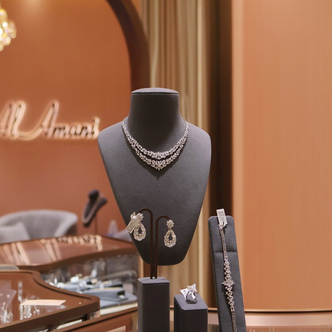 Diamond necklace, earrings, and bracelet displayed on grey velvet stands in a jewelry store.