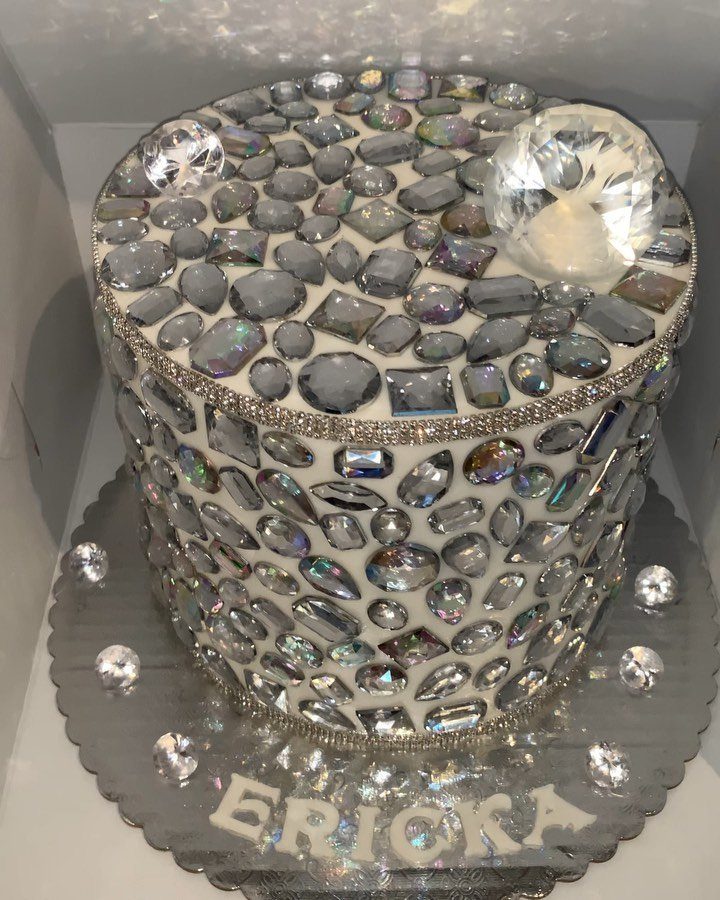 Diamond covered white cake with a large crystal topper on a silver platter.