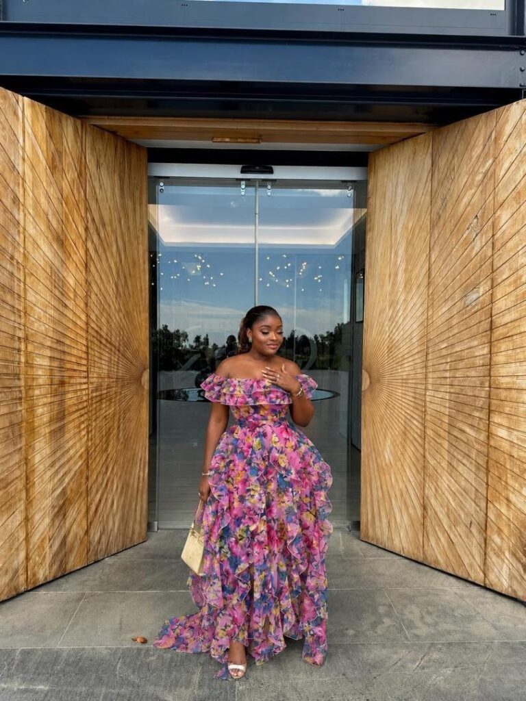 Woman in a colorful floral maxi dress and white strappy high heel sandals.