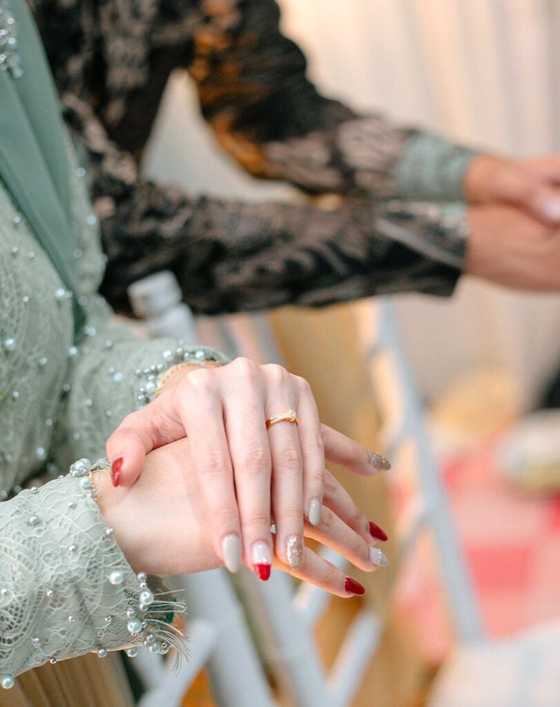 Woman's hands with a gold ring and beaded green lace sleeve.