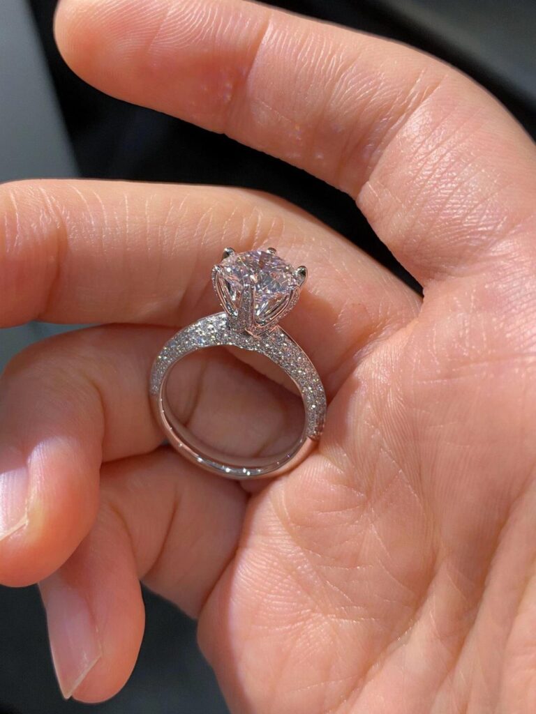 Silver engagement ring with a large diamond held in a person's palm.