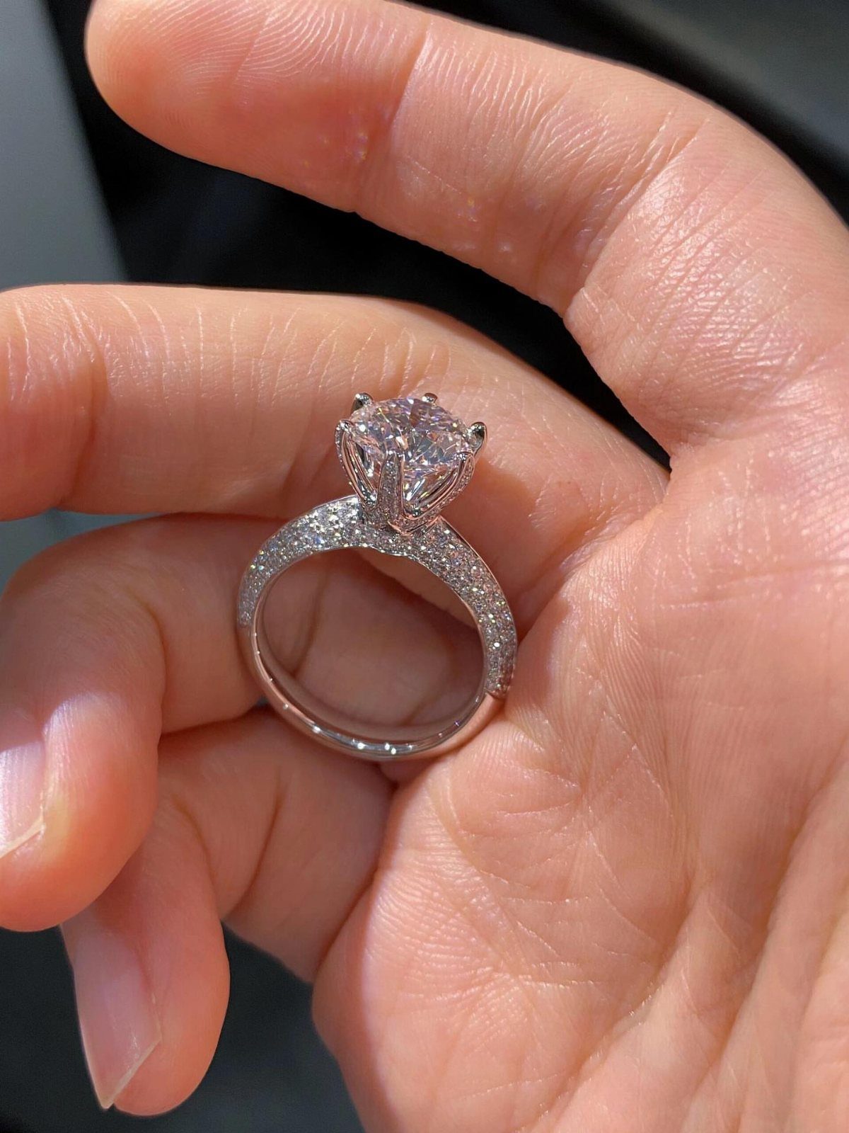 Silver engagement ring with a large diamond held in a person's palm.