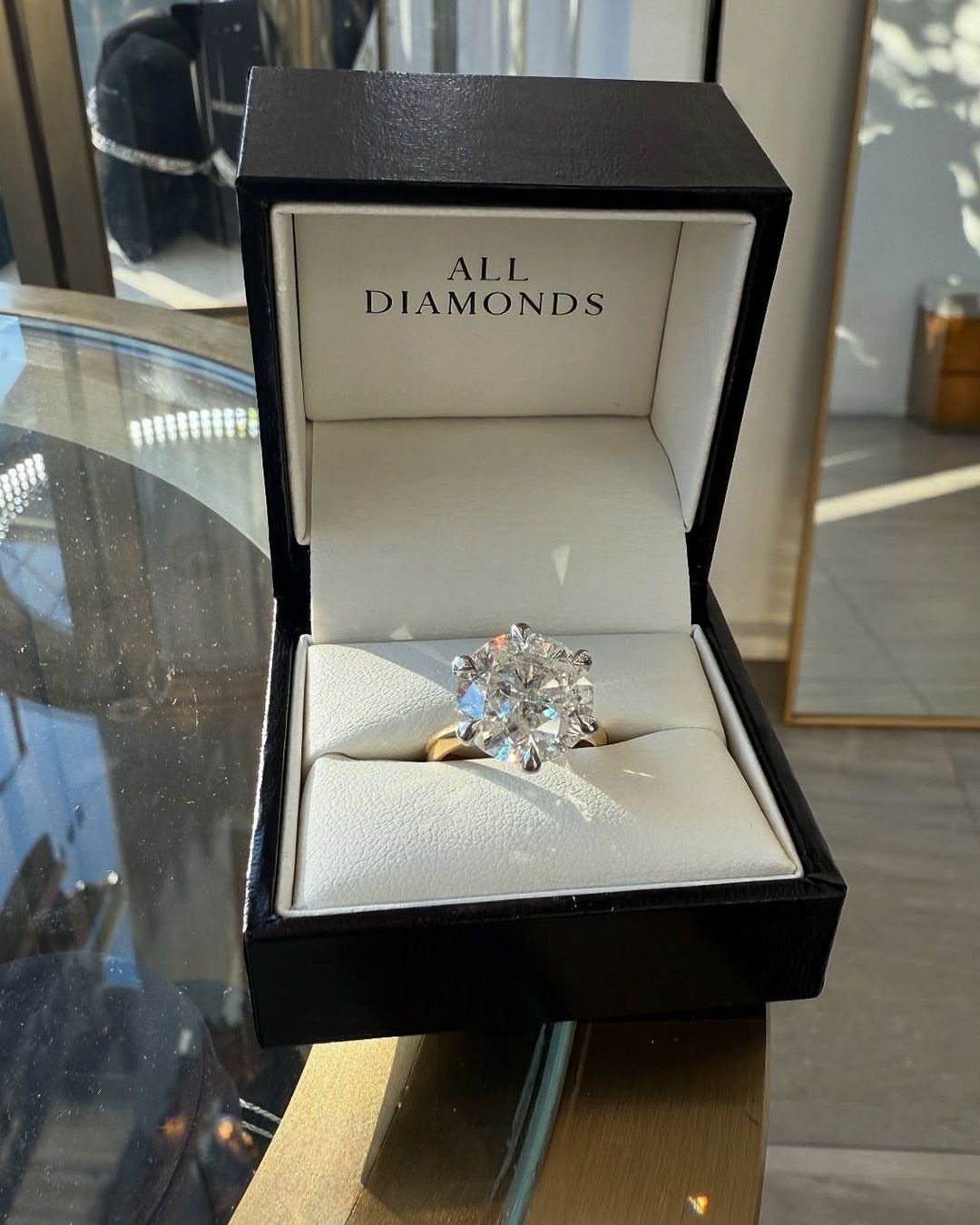 Diamond engagement ring with gold band inside a black jewelry box.