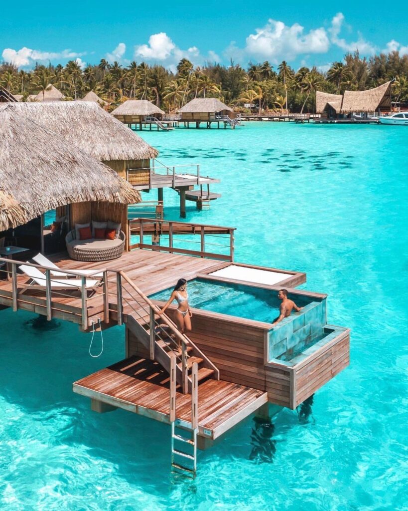 Couple relaxing in a plunge pool at an overwater bungalow in turquoise waters.