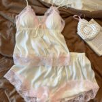White satin pajama set with pink lace trim on brown fabric