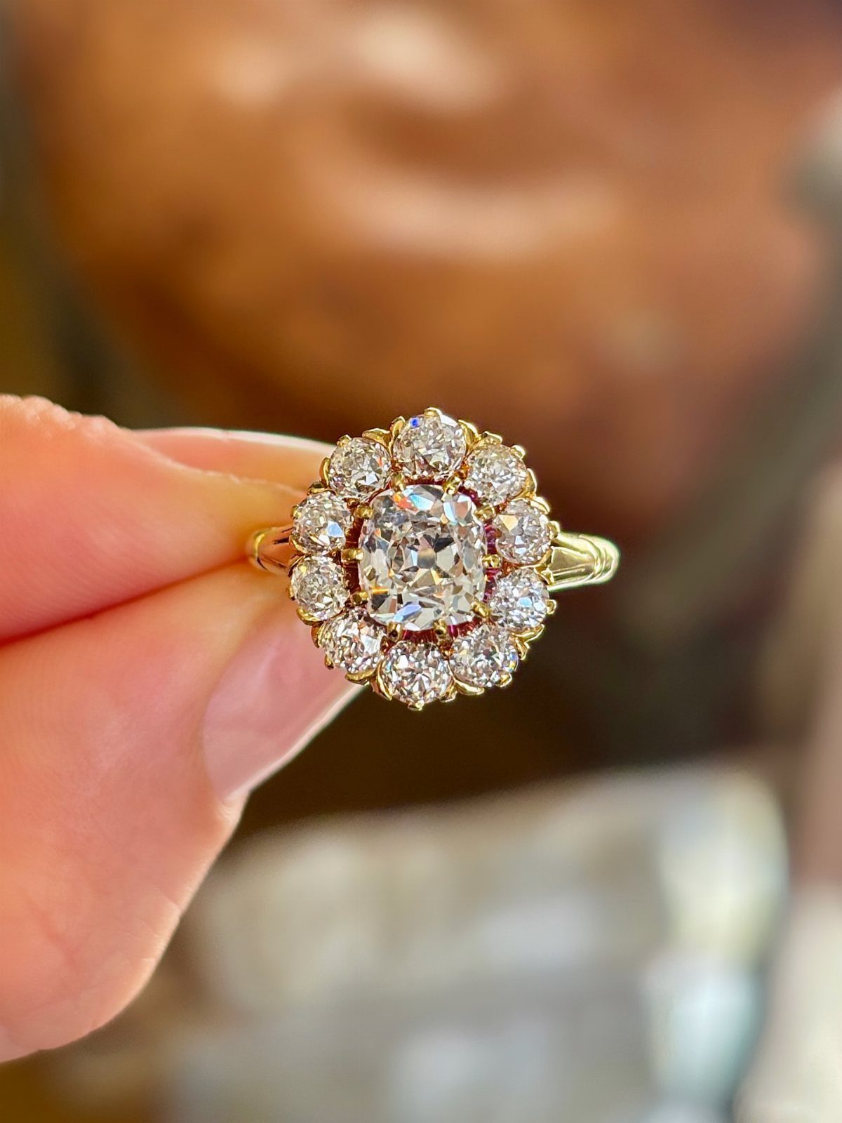 Gold vintage-inspired engagement ring with a central diamond and floral halo setting.