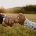 Couple's hands fist bumping showing wedding rings in a sunny outdoor field