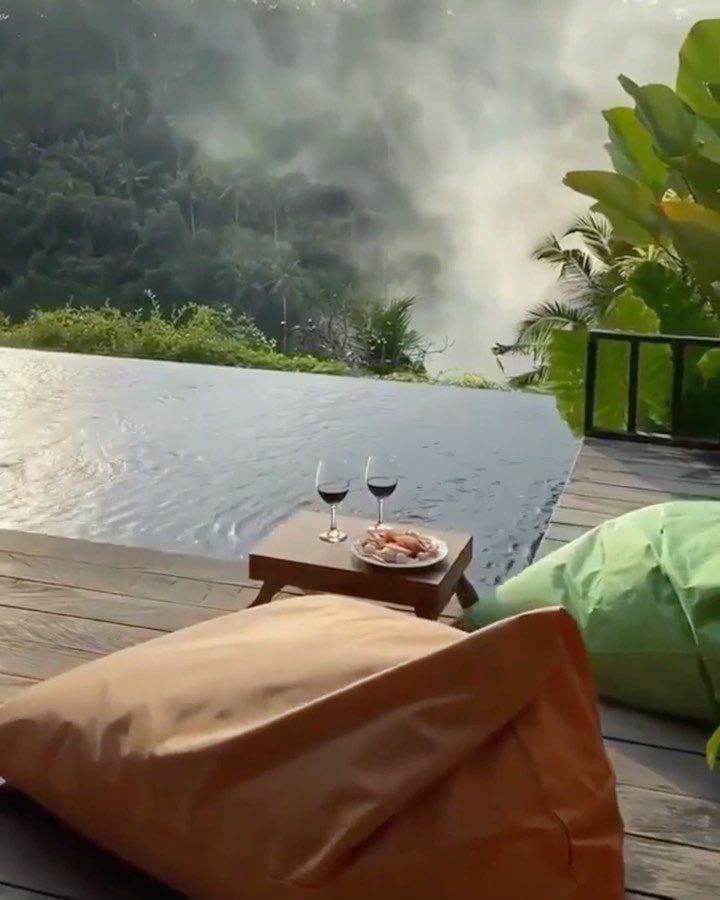 Romantic setup with wine and beanbags overlooking a misty Ubud jungle valley.