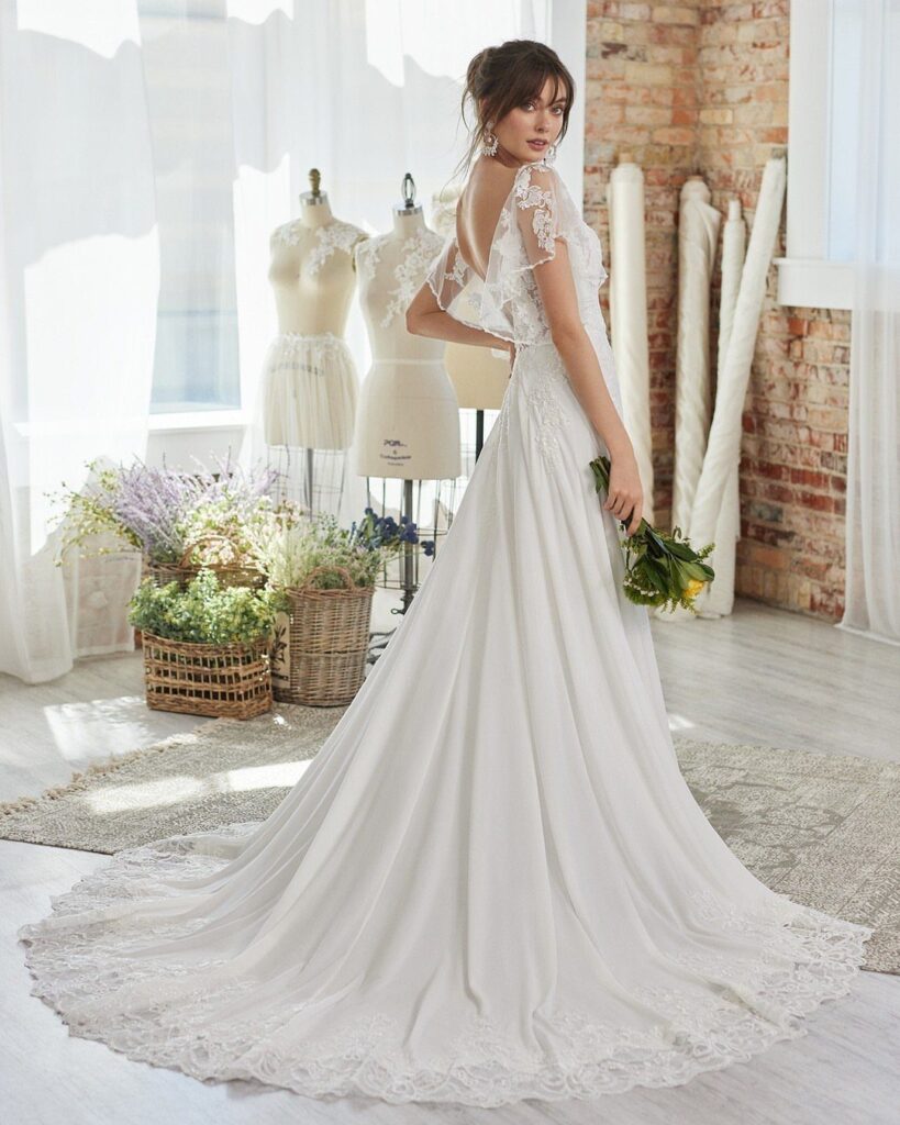 Woman in a white lace wedding dress holding yellow flowers in a bright studio