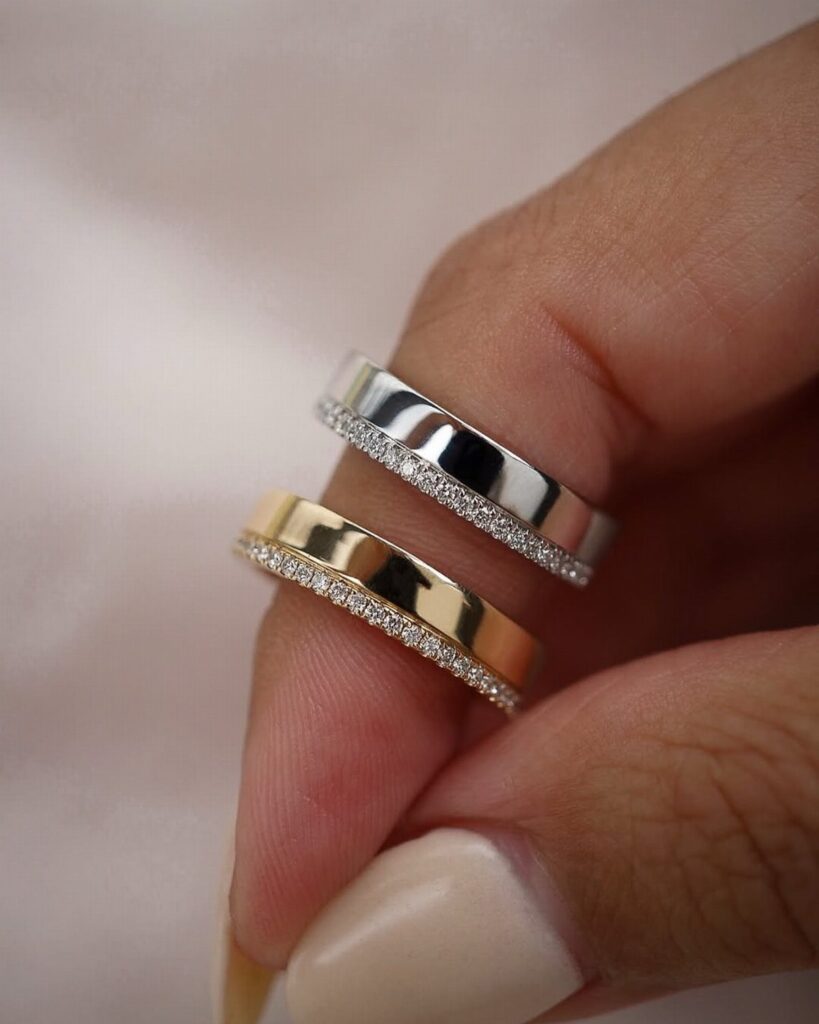 Two wedding bands, one silver and one gold, with pavé diamond accents.